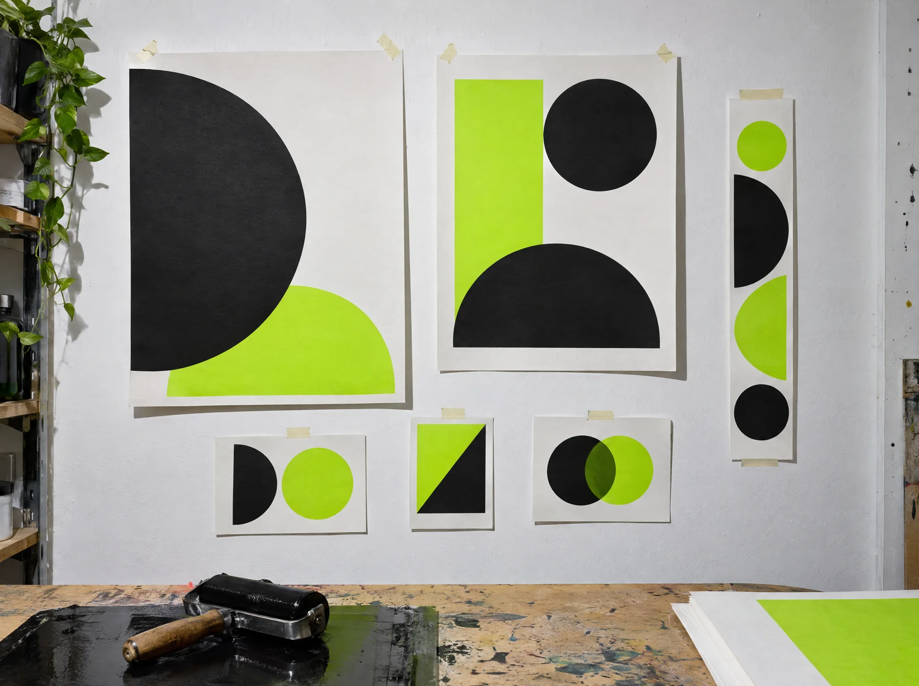 Good Noise poster studies, pinned above the ink-covered studio workbench
